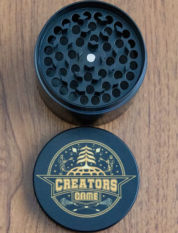 black grinder with gold lacrosse logo seperated into two parts
